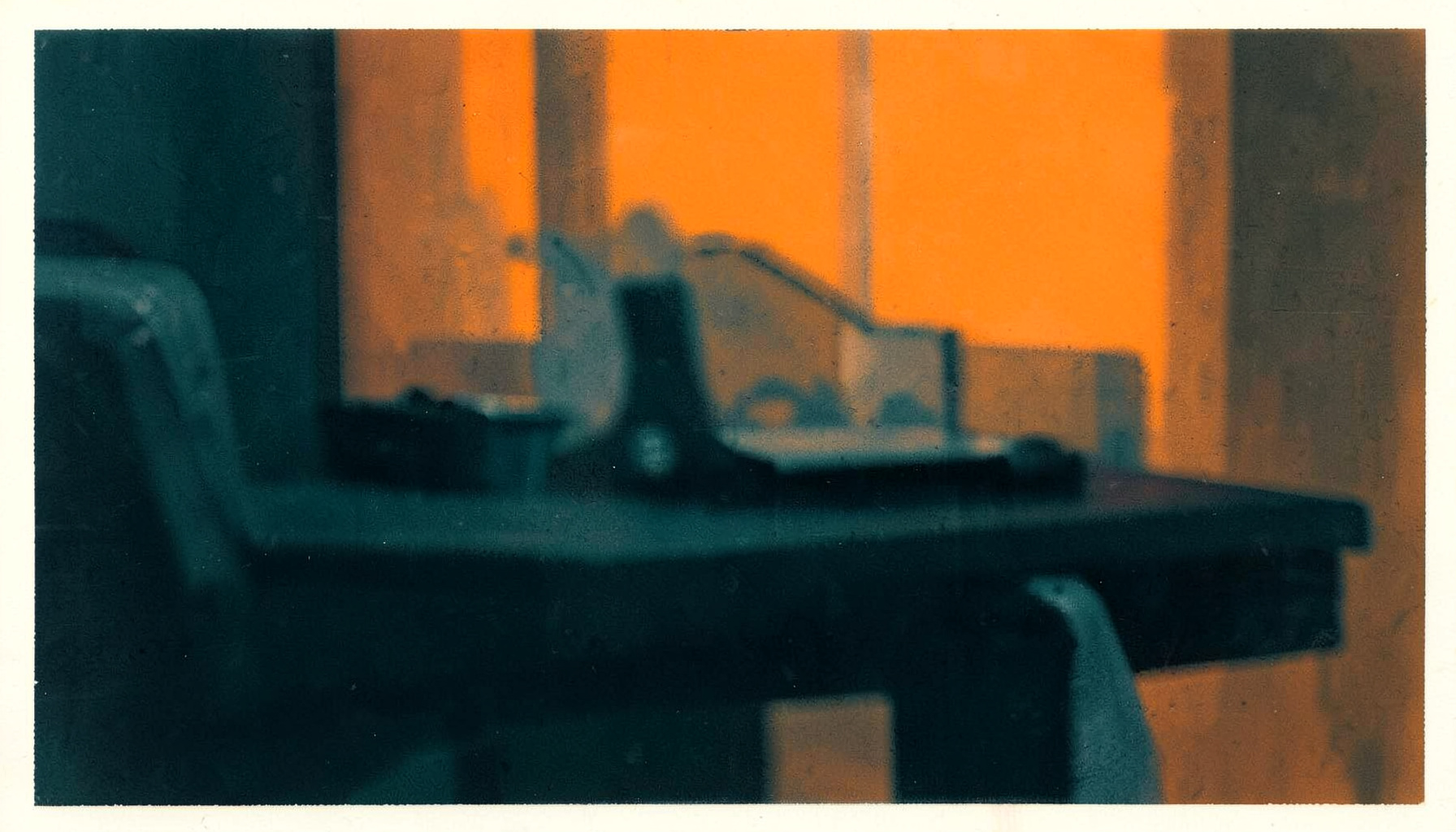 Dark abstract composition with deep teal and charcoal tones, soft blurred shapes suggesting a studio editing desk